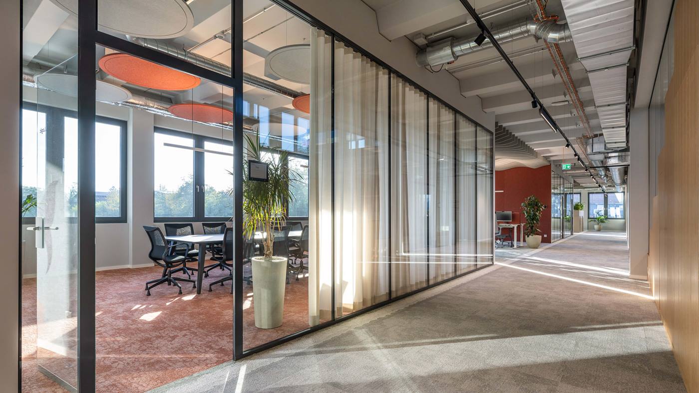 Swisslog Aarau headquarters office interior featuring glass meeting rooms, collaborative workspaces and modern workplace design