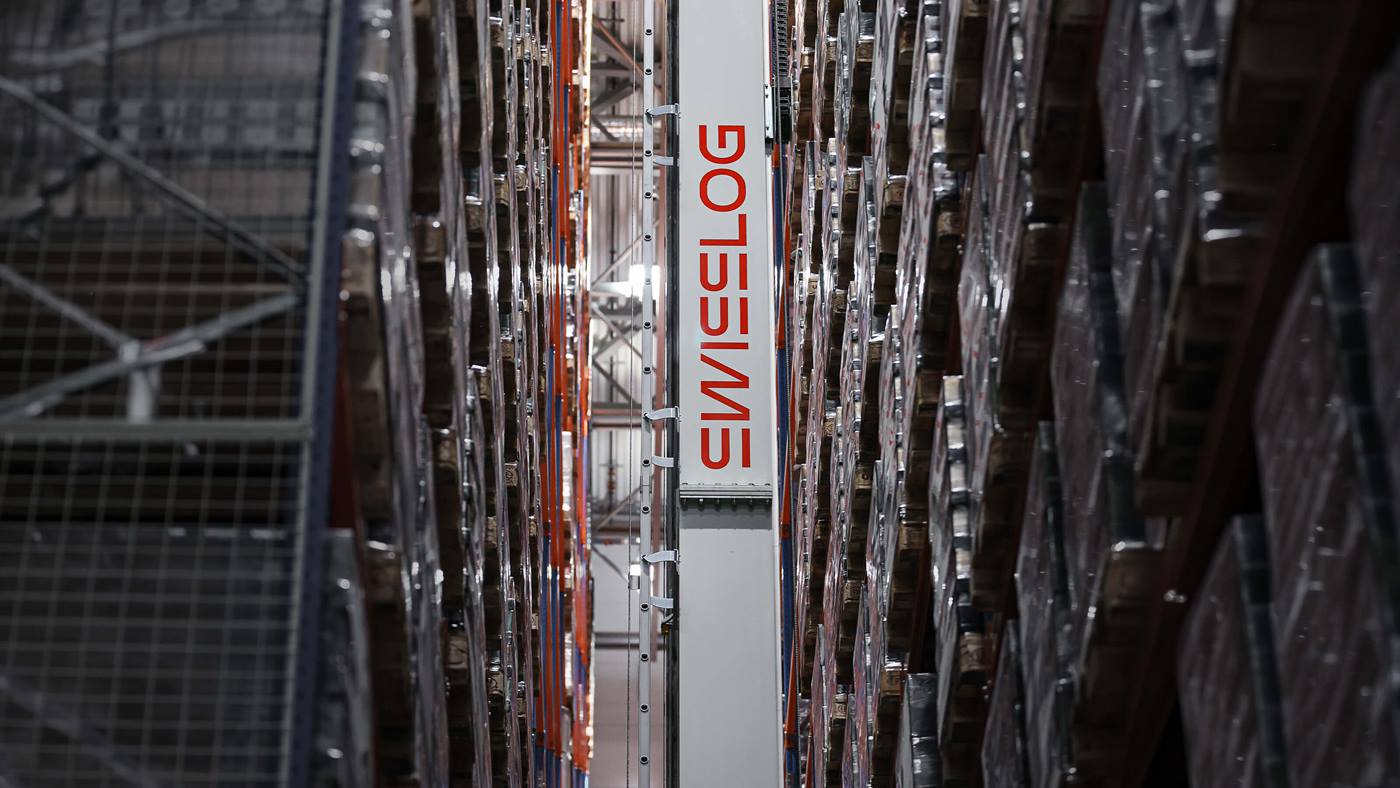 Automated high-bay warehouse aisle with Swisslog Vectura stacker crane handling palletized goods