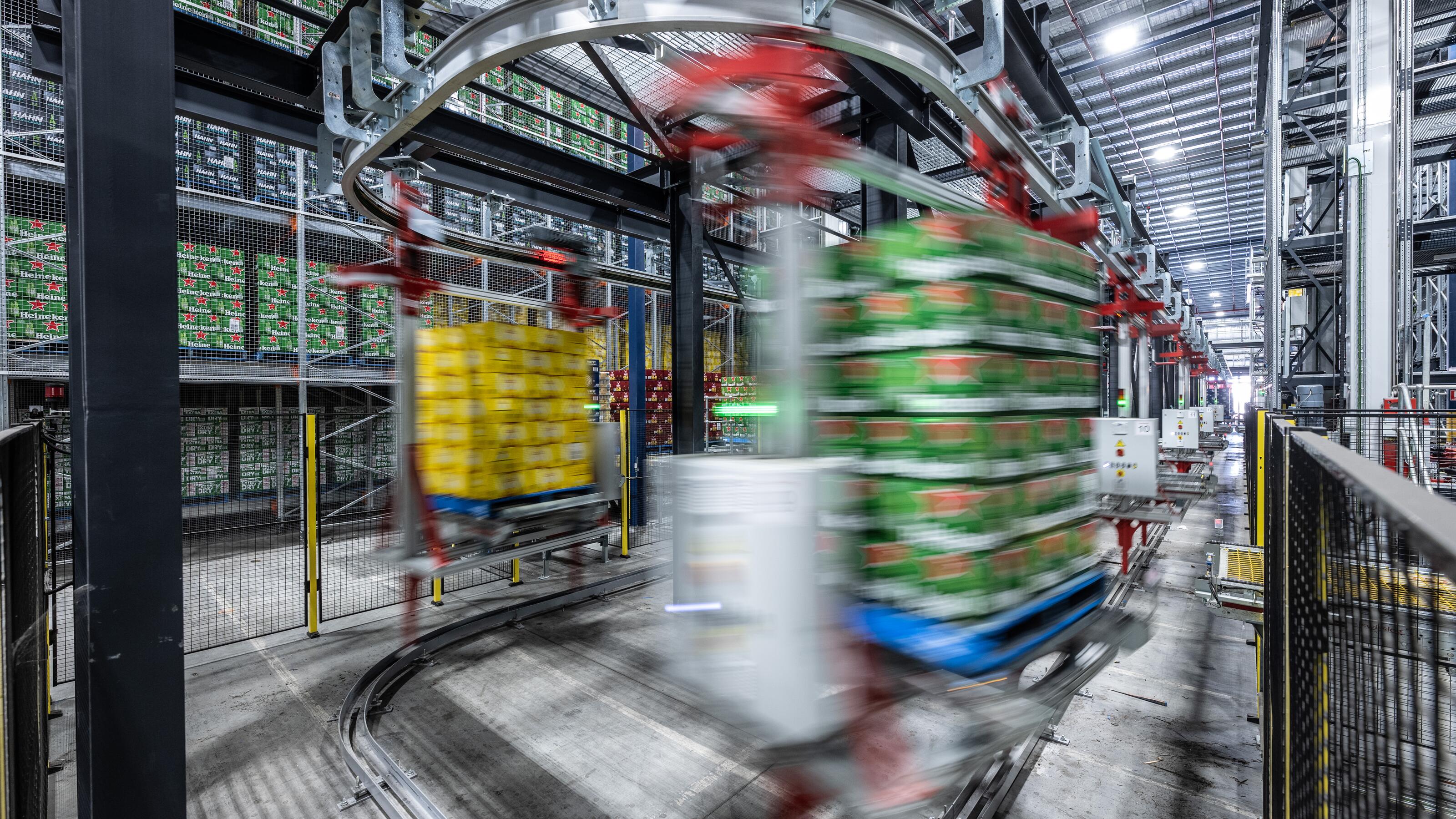 Automated monorail transport system moving pallets through a high-density warehouse distribution centre.