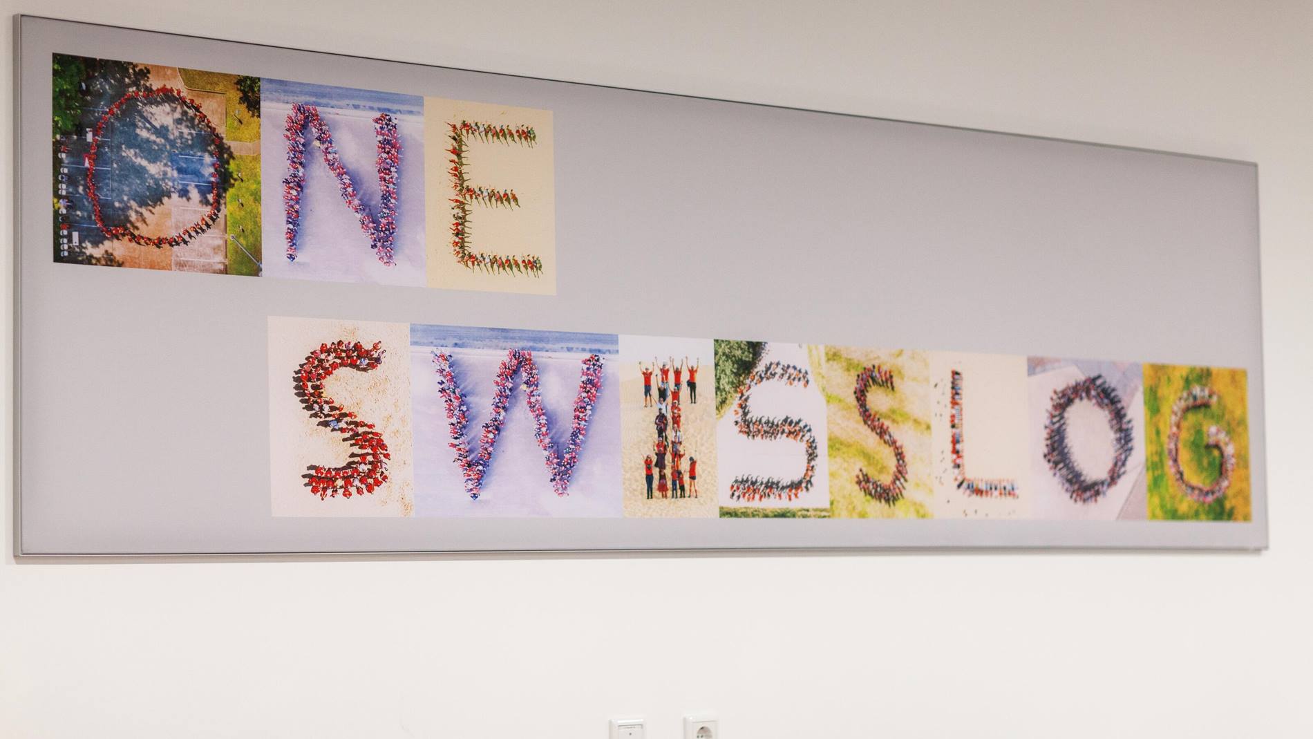 OneSwisslog slogan wall art with photos from employee events across the world